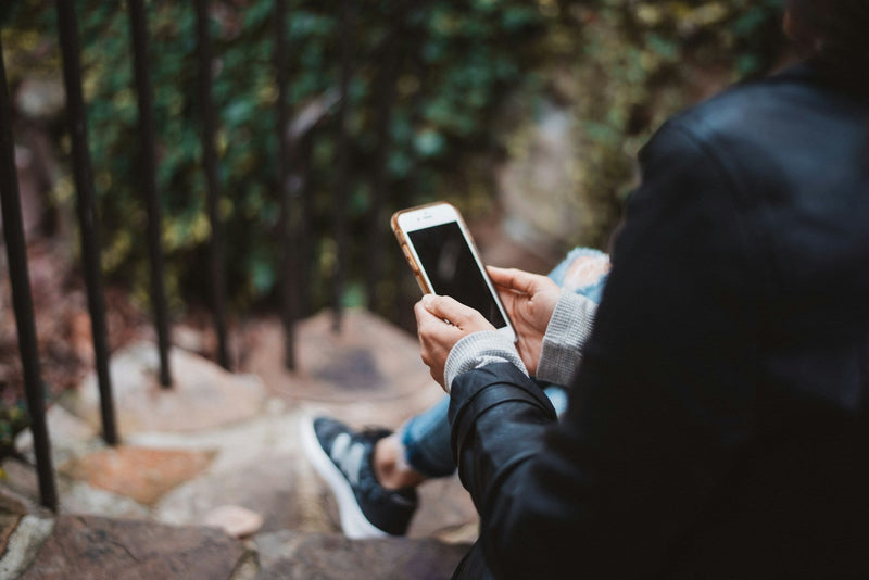 A person sitting on stone steps with a phone in their hands.