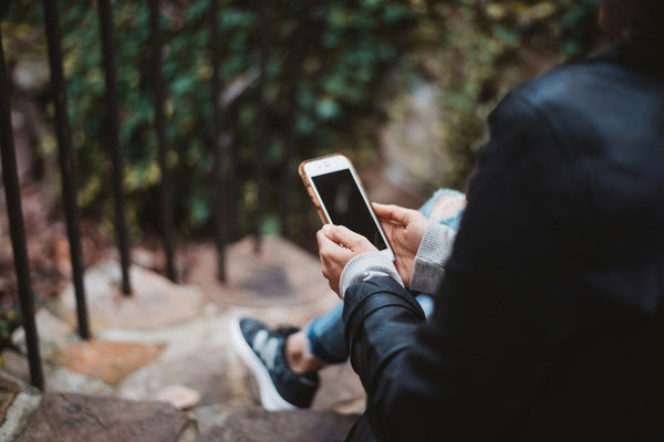 A person sitting on stone steps with a phone in their hands.