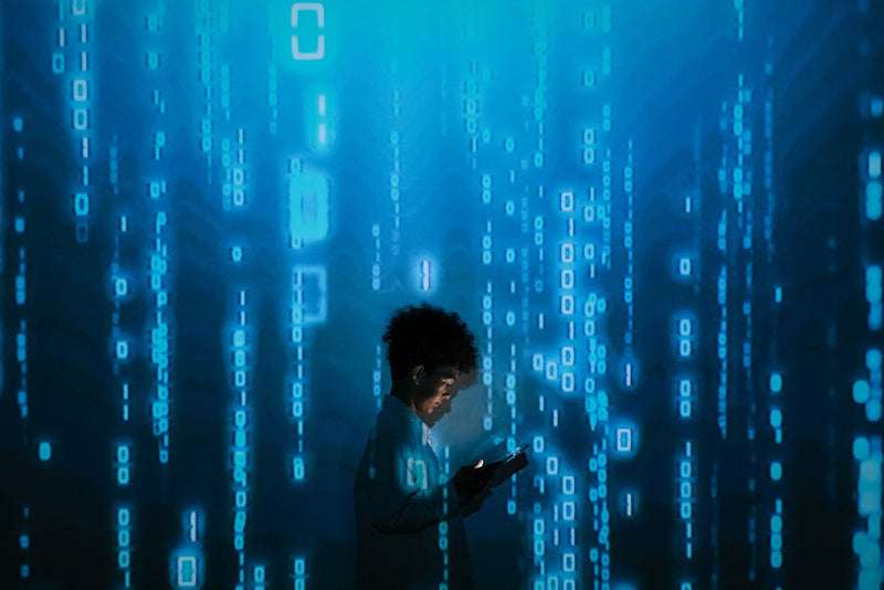 A child standing looking down at a lit up phone screen. It appears as though the child is standing amongst data raining down. 