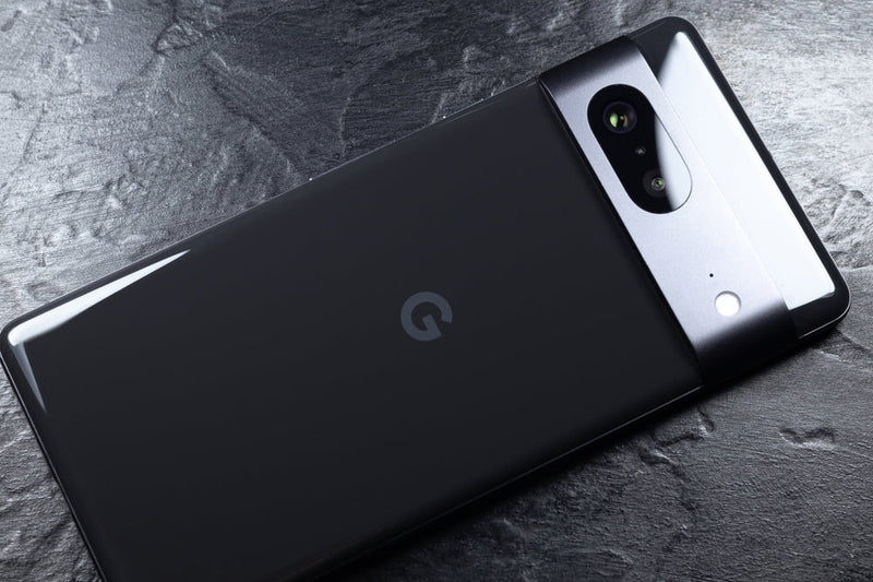 A black Google Pixel phone facedown on a slate surface. 