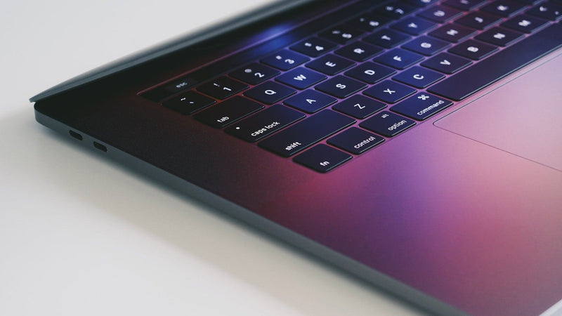 Half open MacBook Pro with purple screensaver reflecting onto keyboard