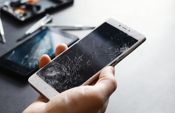 A broken phone being held about refurbishing tools. 