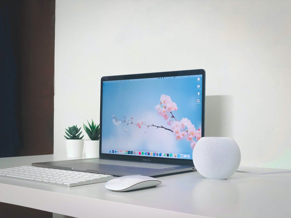 MacBook Pro sitting on white desk with keyboard and mouse in front