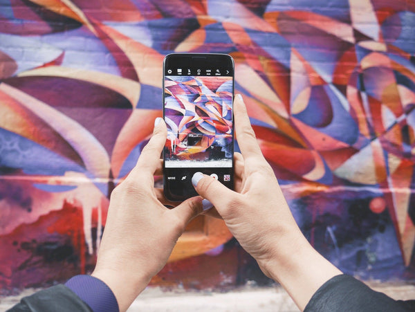 A phone with the camera open pointed towards colourful graffiti on a wall