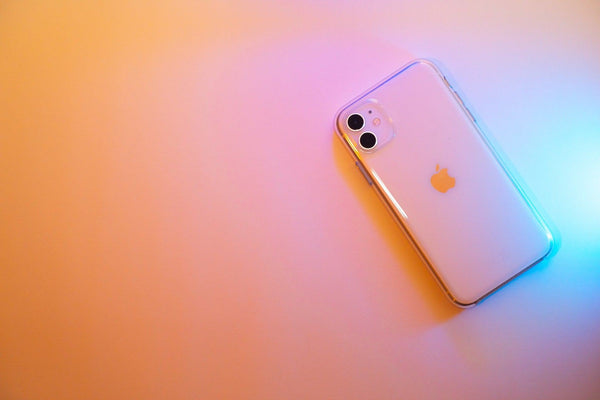 White iPhone 11 flat lay with a pink and blue light