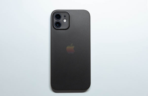 A black iPhone facedown on a white surface.