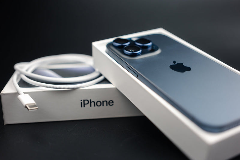 An iPhone merchant box with a charging cord on top. 