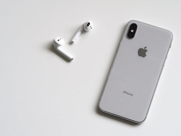 Grey iPhone X laying face down with EarPods next to it 