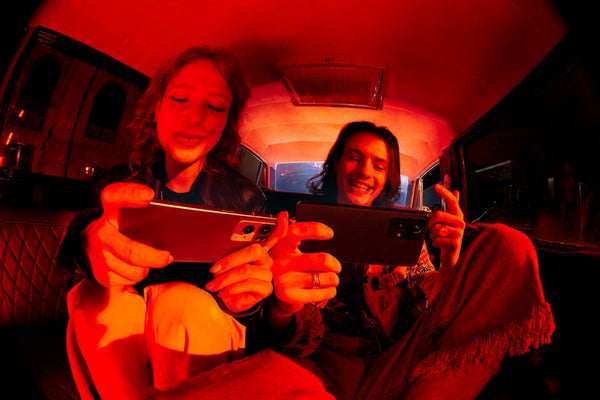 Two people holding an Oppo phone each with red lighting 